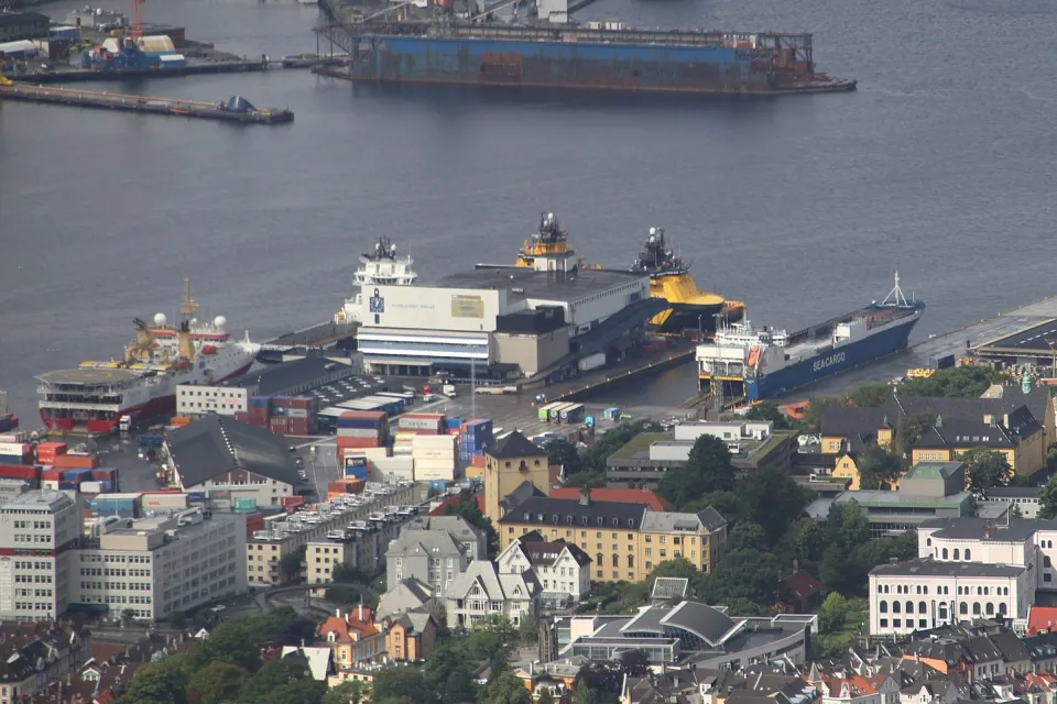 Dokken is a western part of the Port of Bergen (Norway). At Dokken is the large, white Port Warehouse, in which a small brown/black building (in the center of this image) is the WWII German anti-aircraft artillery bunker (RK-ID 212746).